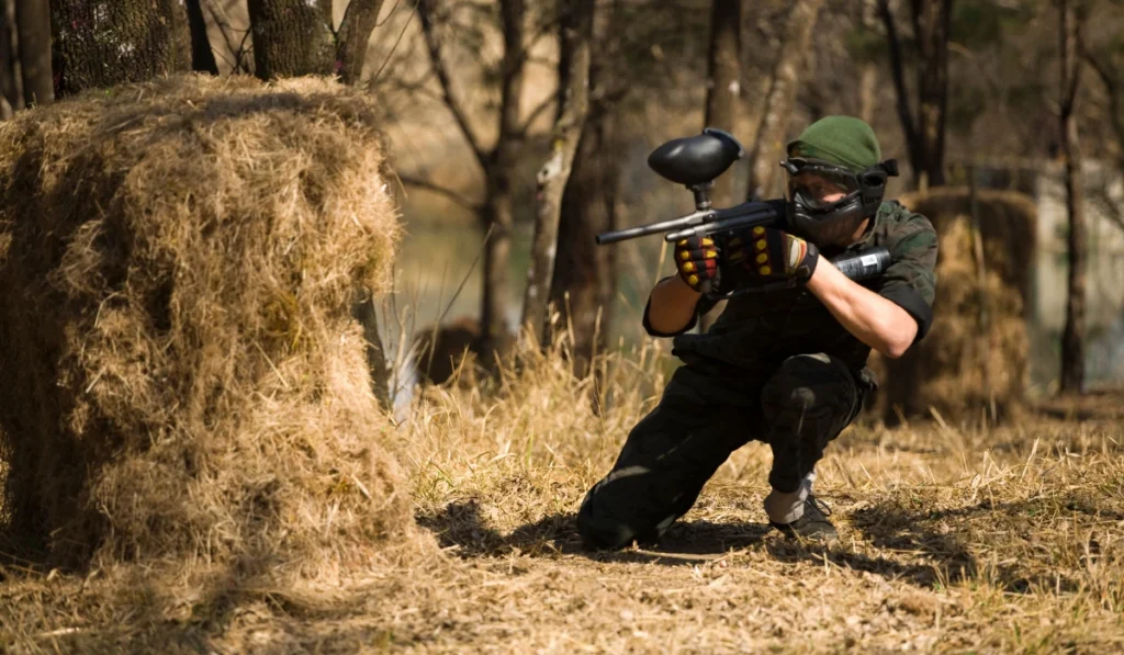 Jugador de paintball evaluando un campo profesional con equipamiento completo
